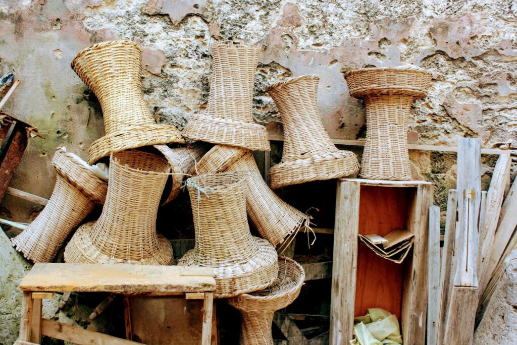 A collection of handwoven wicker baskets stacked against an old, weathered stone wall.