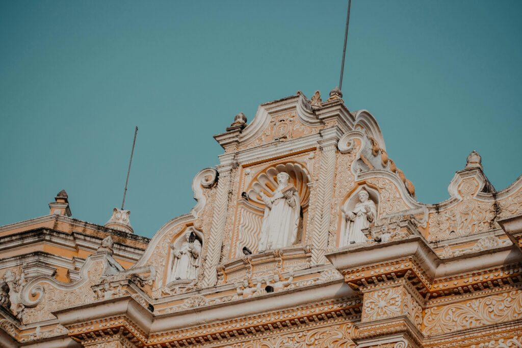 Ornate baroque-style church facade with religious statues and intricate carvings against a clear blue sky.